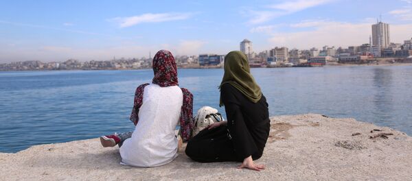 الشابة الفلسطينية سارة أبو طقية (يمين)، 23 عاما، تعمل في مستشفى الأهلي تقضي وقتها مع صديقتها في منياء بحر غزة، 27 نوفمبر/ تشرين الثاني 2019 - سبوتنيك عربي