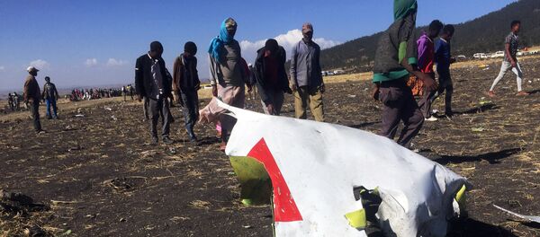 أشخاص يمشون بجوار جزء من الحطام في مكان تحطم طائرة الخطوط الجوية الإثيوبية بالقرب من مدينة بيشوفو جنوب شرق أديس أبابا - سبوتنيك عربي