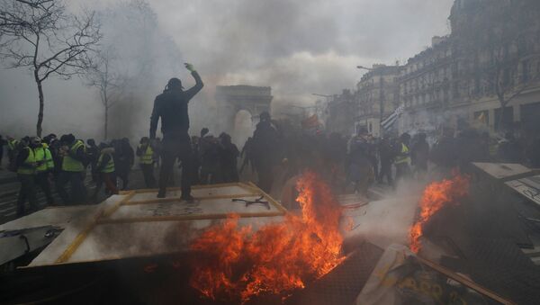متظاهر يقف على حاجز محترق أثناء مظاهرة من قبل حركة السترات الصفراء في باريس - سبوتنيك عربي