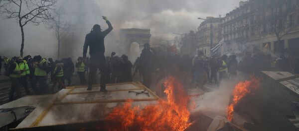 متظاهر يقف على حاجز محترق أثناء مظاهرة من قبل حركة السترات الصفراء في باريس - سبوتنيك عربي
