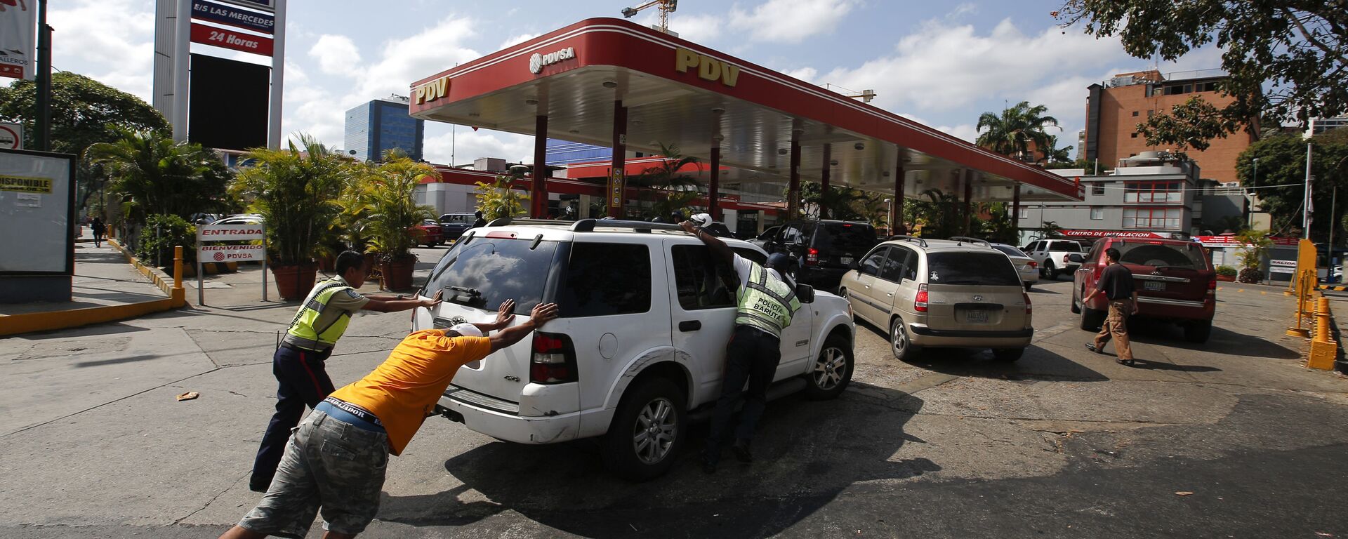 أشخاص يدفعون بالسيارة إلى محطة بنزين، بها مولد كهربائي خاص بها، أثناء انقطاع التيار الكهربائي في كراكاس، 10 مارس/ آذار 2019 - سبوتنيك عربي, 1920, 16.05.2022