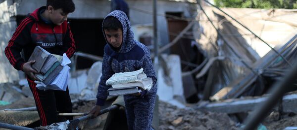 غزة، قطاع غزة، فلسطين - مواطنون غزيون بعد ليلة من قصف الطيران الحربي الإسرائيلي، أطفال يجمعون نسخ من كتب القرآن بعد قصف لمسجد وسط القطاع، 26 مارس/ آذار 2019 - سبوتنيك عربي