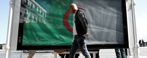 رجل يسير بجوار العلم الوطني الجزائر العاصمة - سبوتنيك عربي