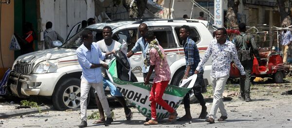 مدنيون يحملون جثة رجل قتل في انفجار سيارة مفخخة بالقرب من فندق في مقديشو - سبوتنيك عربي