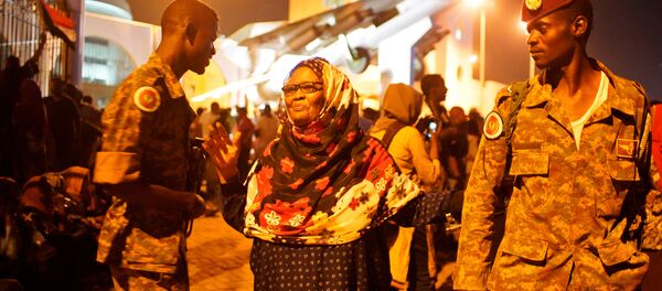 متظاهرة سودانية تسير بين الجيش خلال الاحتفالات بعد تنحي وزير الدفاع عوض بن عوف كرئيس للمجلس العسكري الانتقالي الحاكم في البلاد - سبوتنيك عربي