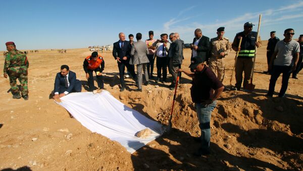 أعضاء من الدفاع المدني العراقي يغطون عظام مقبرة جماعية مكتشفة للأكراد غرب مدينة السماوة - سبوتنيك عربي