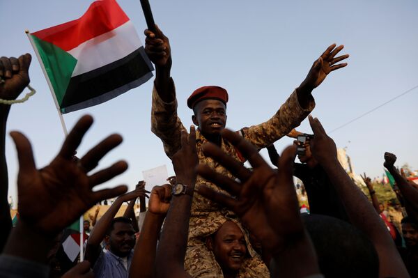 جندي سوداني يجلس على أكتاف أحد المتظاهرين وهو يهتف مع الحشد خارج وزارة الدفاع في الخرطوم - سبوتنيك عربي