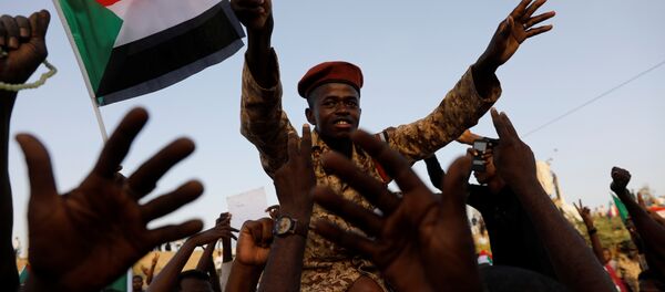 جندي سوداني يجلس على أكتاف أحد المتظاهرين وهو يهتف مع الحشد خارج وزارة الدفاع في الخرطوم - سبوتنيك عربي