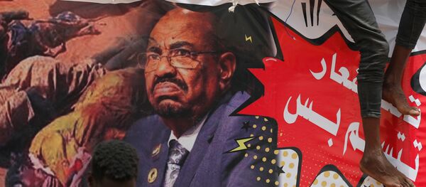 متظاهرون في السودان يرفعون لافتات عليها صورة الرئيس المعزور عمر البشير - سبوتنيك عربي