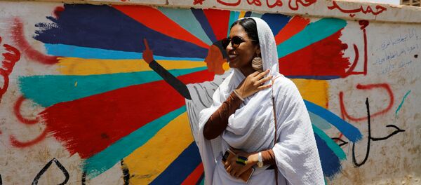 آلاء صلاح تقف أمام لوحة جدارية تصورها أمام وزارة الدفاع في الخرطوم - سبوتنيك عربي