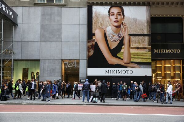 المارة يعبرون متظاهرين يحملون لافتات من برج ترامب في الجادة الخامسة بنيويورك - سبوتنيك عربي