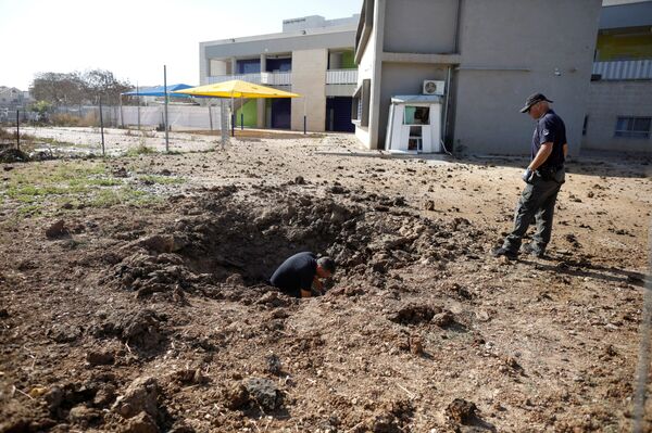 ضباط شرطة إسرائيليين يتفقدون موقع سقط فيه صاروخ أطلق من غزة - سبوتنيك عربي