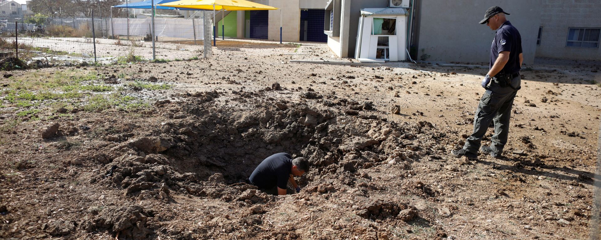 ضباط شرطة إسرائيليين يتفقدون موقع سقط فيه صاروخ أطلق من غزة - سبوتنيك عربي, 1920, 13.05.2023