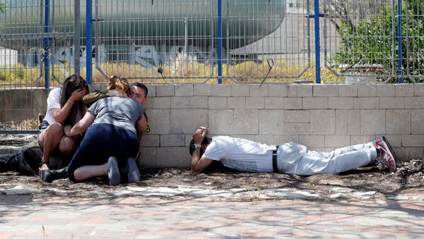 إسرائيليون يستترون وهم يسمعون صفارات الإنذار تحذر من الصواريخ القادمة من غزة في مدينة عسقلان جنوبي إسرائيل - سبوتنيك عربي