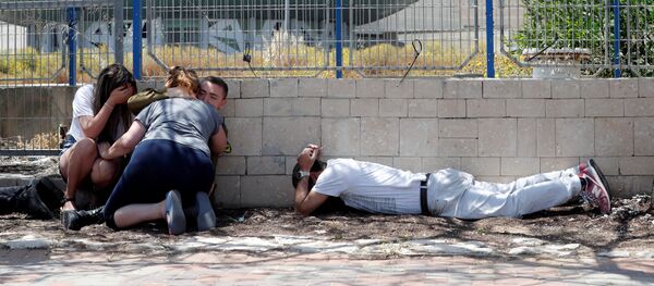 إسرائيليون يستترون وهم يسمعون صفارات الإنذار تحذر من الصواريخ القادمة من غزة في مدينة عسقلان جنوبي إسرائيل - سبوتنيك عربي