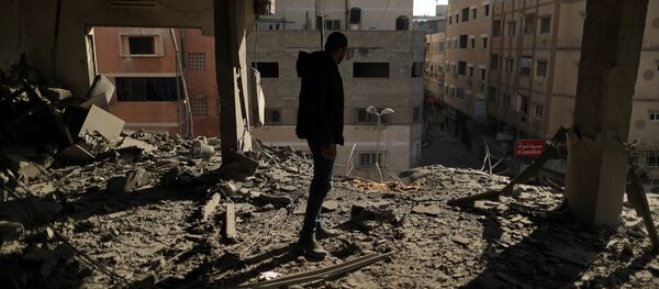 فلسطيني يتفقد مبنى دمرته الضربات الجوية الإسرائيلية في مدينة غزة - سبوتنيك عربي