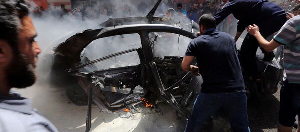 يحاول الفلسطينيون إطفاء حريق في سيارة أحد قادة حماس حامد أحمد عبد الخضري الذي قتل في غارة جوية إسرائيلية في مدينة غزة - سبوتنيك عربي