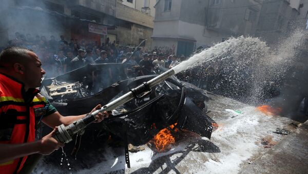 عضو في الدفاع المدني الفلسطيني يطفئ حريقا في سيارة القيادي الحمساوي حامد أحمد عبد الخضري الذي قتل في غارة جوية إسرائيلية في مدينة غزة - سبوتنيك عربي