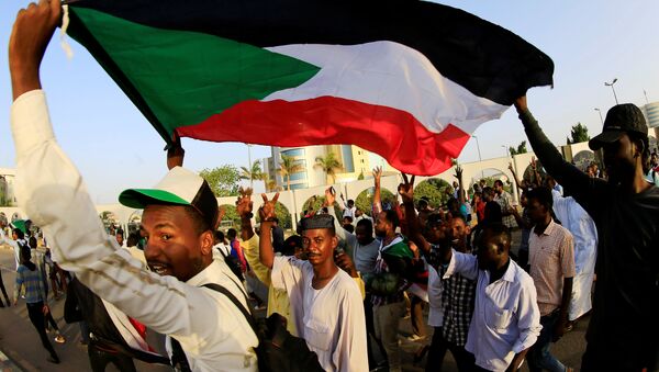 متظاهرون سودانيون يحملون العلم الوطني وهم يهتفون قبل الإفطار في اليوم الأول من شهر رمضان أمام مجمع وزارة الدفاع في الخرطوم - سبوتنيك عربي