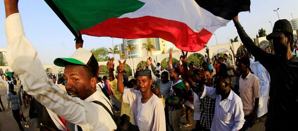 متظاهرون سودانيون يحملون العلم الوطني وهم يهتفون قبل الإفطار في اليوم الأول من شهر رمضان أمام مجمع وزارة الدفاع في الخرطوم - سبوتنيك عربي