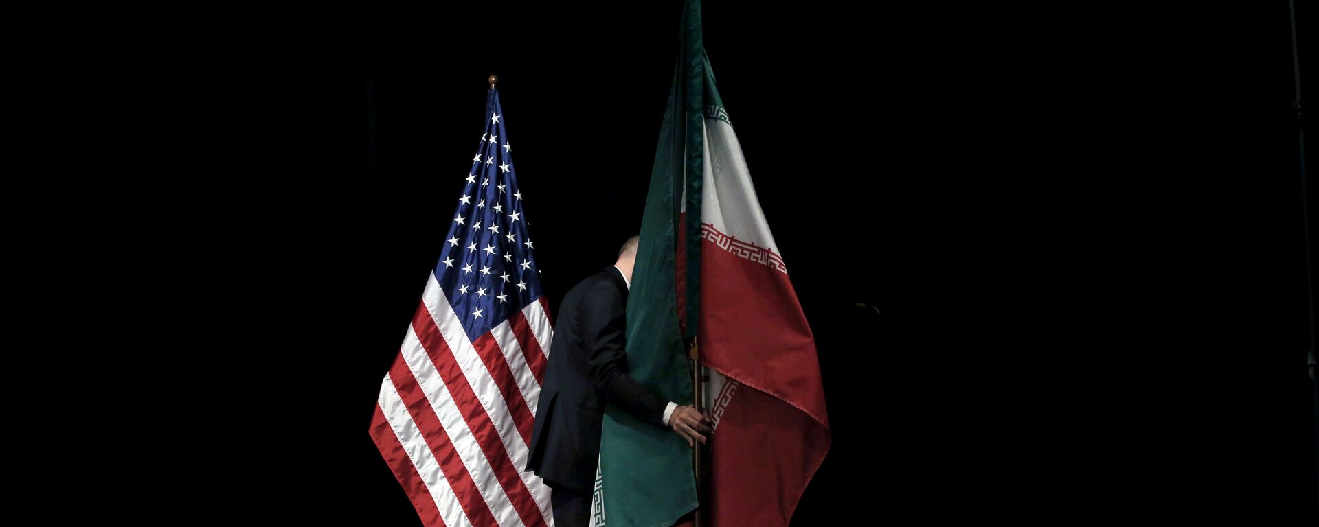 موظف يرفع العلم الإيراني من المسرح بعد صورة جماعية مع وزراء الخارجية وممثليهم خلال المحادثات النووية الإيرانية في مركز فيينا الدولي في فيينا - سبوتنيك عربي, 1920, 20.06.2021