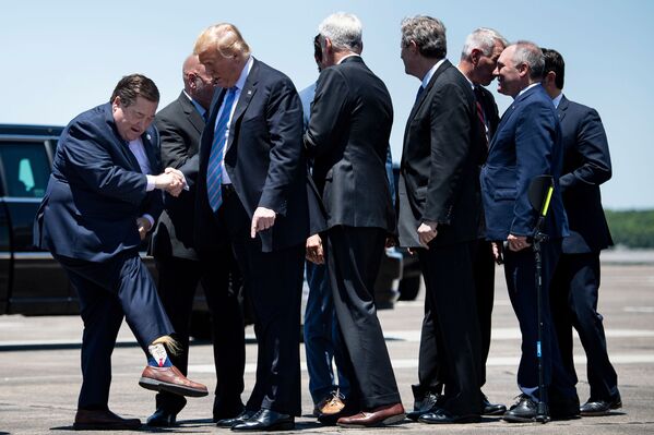 حاكم لويزيانا بيلي نونجيسر يكشف للرئيس الأمريكي دونالد ترامب عن جواربه بعد وصول الرئيس إلى مطار تشينولت الدولي في 14 مايو/ أيار 2019 بولاية لويزيانا - سبوتنيك عربي