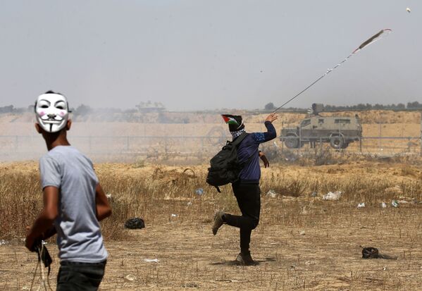 شباب فلسطينيون يقذفون الحجارة في شرق خان يونس، جنوب قطاع غزة، أثناء إحياء الذكرى الـ 71 للنكبة، 15 مايو/ أيار 2019 - سبوتنيك عربي