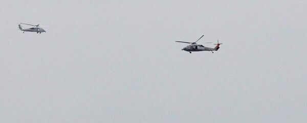 زورق للحرس الثوري الإيراني بالقرب من حاملة الطائرات الأمريكية جورج دبليو بوش في مضيق هرمز بينما تحلق مروحيات تابعة للبحرية الأمريكية في مكان قريب - سبوتنيك عربي