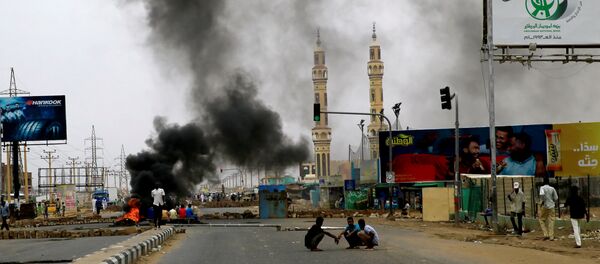متظاهرون سودانيون بالقرب من إطارات محترقة مستخدمة لإقامة حاجز في أحد الشوارع مطالبين المجلس العسكري الانتقالي في البلاد بتسليم السلطة للمدنيين - سبوتنيك عربي