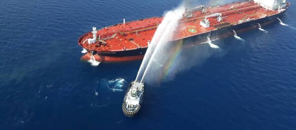 قارب من البحرية الإيرانية يحاول إطفاء نيران ناقلة النفط بعد أن تعرضت للهجوم في خليج عمان - سبوتنيك عربي