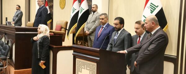 رئيس البرلمان العراقي محمد الحلبوسي يقف مع الوزراء المفوضين حديثاً خلال مراسم أداء اليمين في مقر البرلمان في بغداد - سبوتنيك عربي