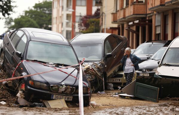 امرأة تتحدث على الهاتف بجوار السيارات المدمرة بعد هطول أمطار غزيرة في تافالا، إسبانيا ، 9 يوليو/ تموز 2019 - سبوتنيك عربي