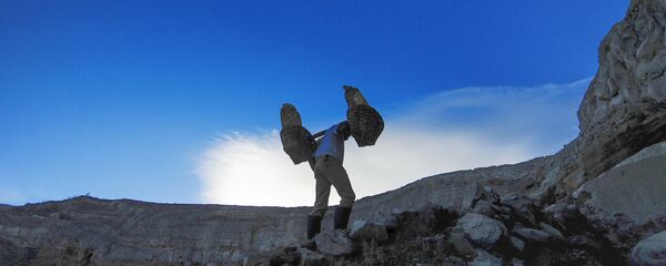 عامل منجم ينقل سلال الكبريت الصلب من مقلع يقع على البركان النشط كواه آيجن (Kawah Ijen) في إندونيسيا. يسود الفقر في المنطقة، والعمال ليس لديهم ملابس خاصة لهذه الوظيفة، ومتوسط الأجور، يتراوح بين 7-8 دولارات في اليوم. يقوم كل عامل منجم بنقل 75-90 كغم من الكبريت من المنجم في رحلة واحدة. - سبوتنيك عربي