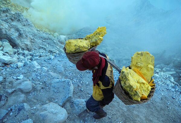 عامل منجم ينقل سلال الكبريت الصلب من مقلع يقع على البركان النشط كواه آيجن (Kawah Ijen) في إندونيسيا. يسود الفقر في المنطقة، والعمال ليس لديهم ملابس خاصة لهذه الوظيفة، ومتوسط الأجور، يتراوح بين 7-8 دولارات في اليوم. يقوم كل عامل منجم بنقل 75-90 كغم من الكبريت من المنجم في رحلة واحدة. - سبوتنيك عربي