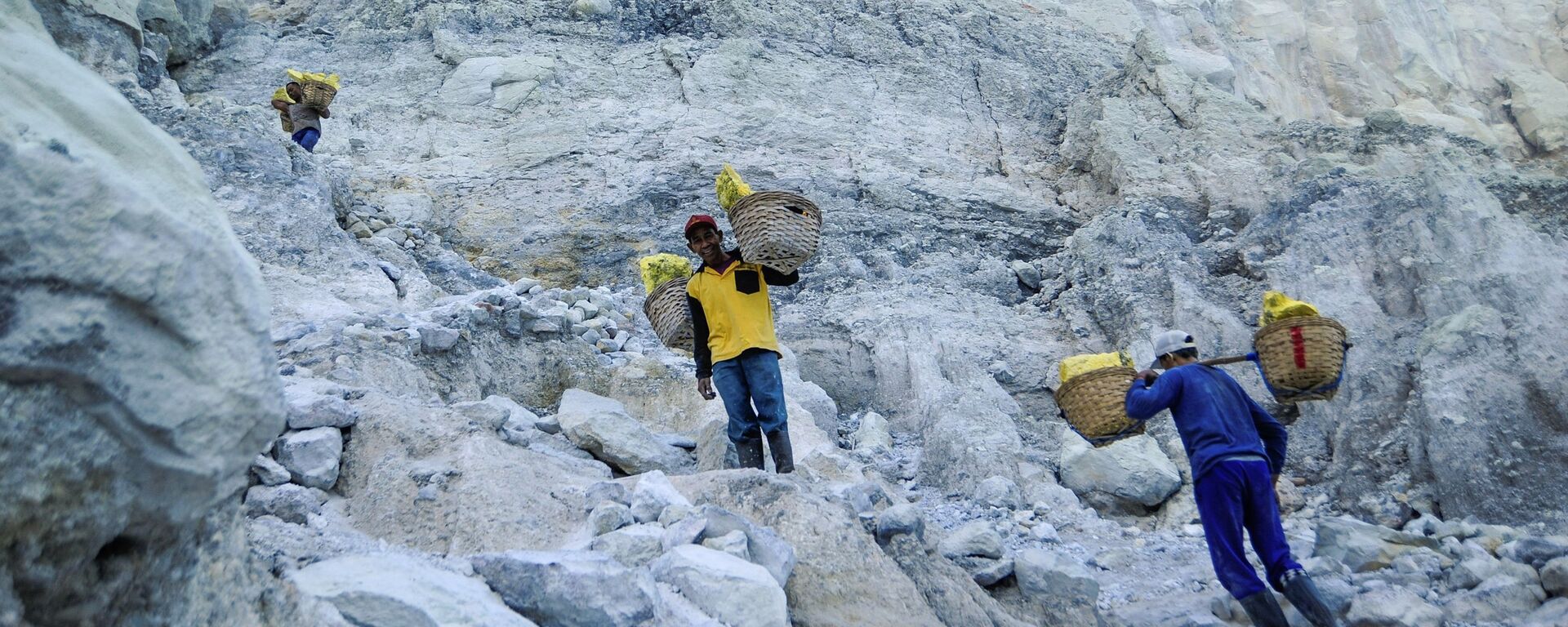 عامل منجم ينقل سلال الكبريت الصلب من مقلع يقع على البركان النشط كواه آيجن (Kawah Ijen) في إندونيسيا. يسود الفقر في المنطقة، والعمال ليس لديهم ملابس خاصة لهذه الوظيفة، ومتوسط الأجور، يتراوح بين 7-8 دولارات في اليوم. يقوم كل عامل منجم بنقل 75-90 كغم من الكبريت من المنجم في رحلة واحدة. عامل منجم ينقل سلال الكبريت الصلب من مقلع يقع على البركان النشط كواه آيجن (Kawah Ijen) في إندونيسيا. يسود الفقر في المنطقة، والعمال ليس لديهم ملابس خاصة لهذه الوظيفة، ومتوسط الأجور، يتراوح بين 7-8 دولارات في اليوم. يقوم كل عامل منجم بنقل 75-90 كغم من الكبريت من المنجم في رحلة واحدة. - سبوتنيك عربي, 1920, 14.02.2022