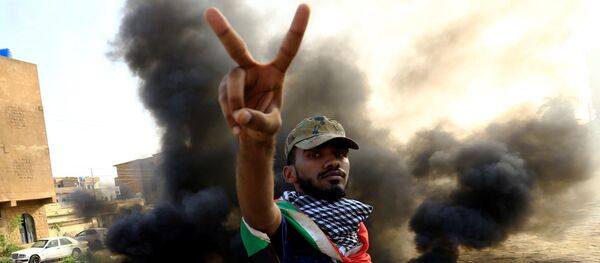 متظاهر يحرق الإطارات أثناء مظاهرة مناهضة لتقرير النائب العام عن فض الاعتصام في الخرطوم - سبوتنيك عربي