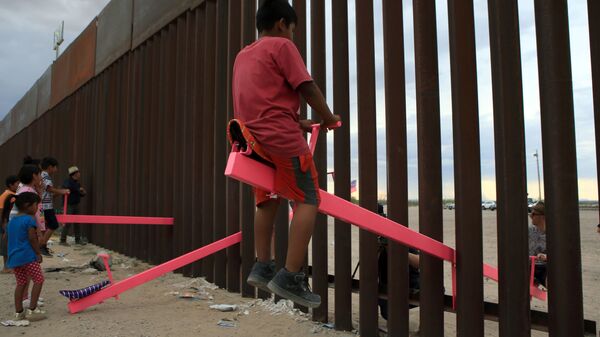 العائلات الأمريكية والمكسيكية تلعب لعبة تسمى صعودًا وهبوطًا (تأرجح الأرجوحة) عبر الحدود المكسيكية مع الولايات المتحدة في منطقة أنابرا في سيوداد خواريز، ولاية تشيهواهوا، المكسيك في 28 يوليو/ حزيران 2019 - سبوتنيك عربي
