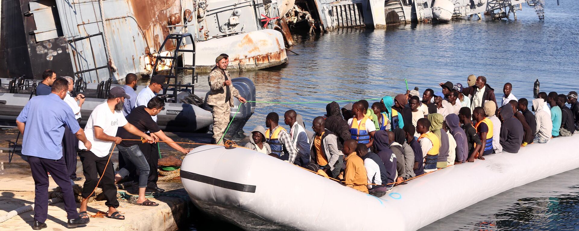  خفر السواحل الليبي يقوم بسحب قارب يحمل مهاجرين أفارقة، تم إنقاذهم أثناء محاولتهم الوصول إلى أوروبا بطريقة غير شرعية، في قاعدة بحرية بالقرب من العاصمة طرابلس في 29 سبتمبر/ أيلول 2015. - سبوتنيك عربي, 1920, 12.06.2023