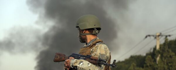 صورة أرشيفية لجندي أفغاني، ودخان متصاعد جراء حادث إرهابي. - سبوتنيك عربي