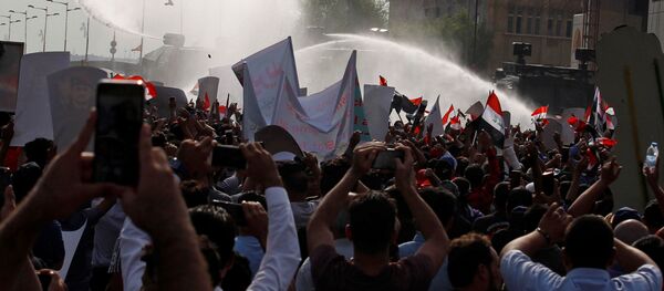 المتظاهرون يتفرقون بينما تستخدم قوات الأمن العراقية المياه خلال مظاهرة احتجاج على فساد الحكومة وسط استياء من قلة الوظائف والخدمات في ميدان التحرير في بغداد - سبوتنيك عربي