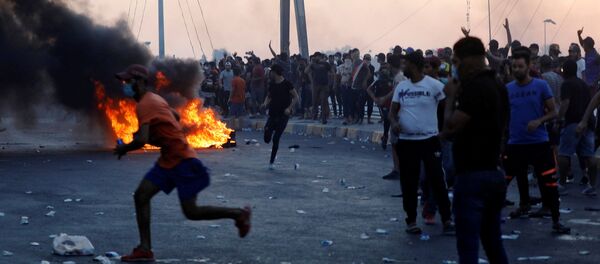 المتظاهرون يتجمعون خلال احتجاج بعد رفع حظر التجول بعد أربعة أيام من الاحتجاجات المناهضة للحكومة على مستوى البلاد والتي تحولت إلى عنف في بغداد - سبوتنيك عربي