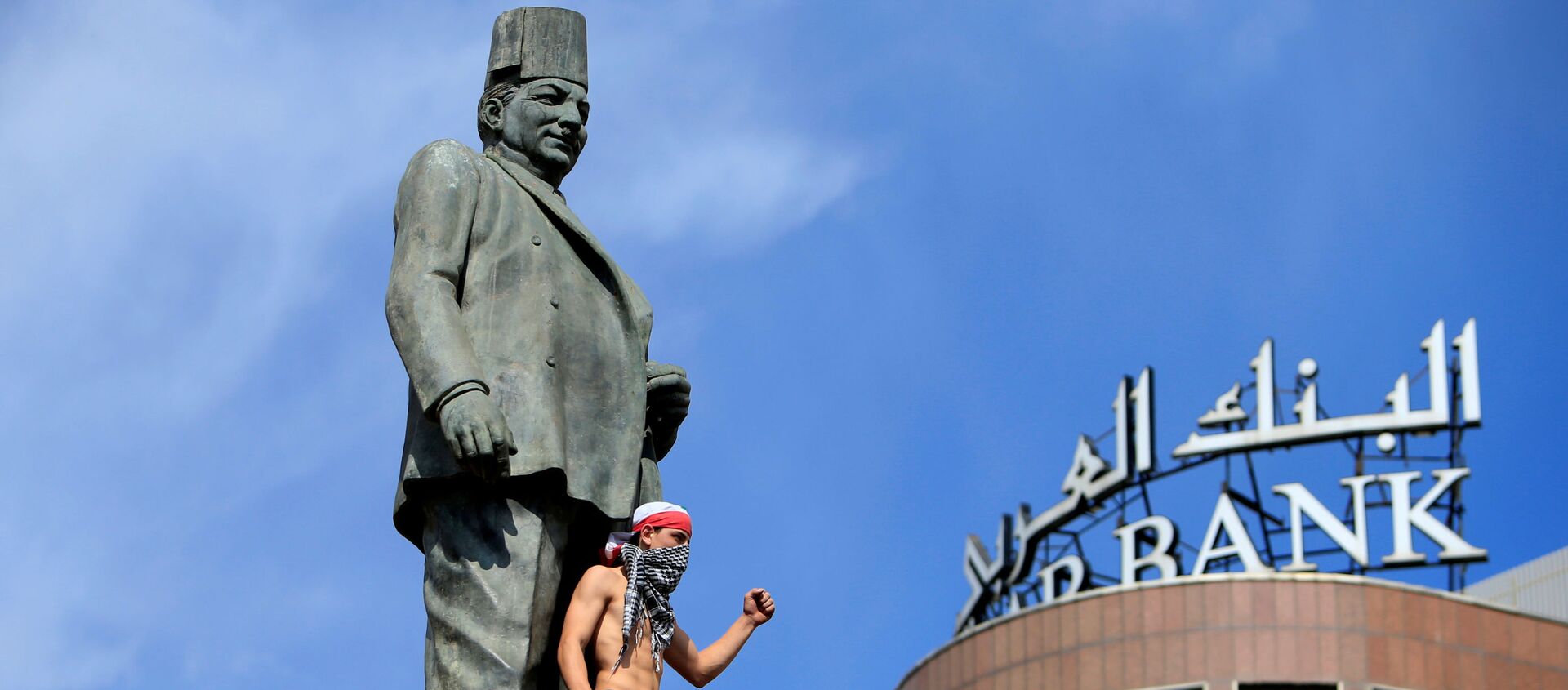 أحد المتظاهرين يلوح أثناء وقوفه في تمثال رياض الصلح أثناء مظاهرة مناهضة للحكومة بالقرب من قصر الحكومة في بيروت - سبوتنيك عربي, 1920, 16.09.2020