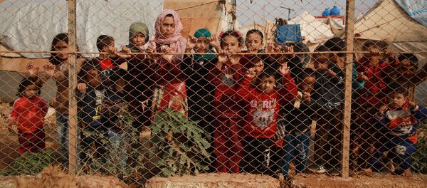 أطفال سوريون مهجرون يقفون خلف سياج مخيم كفر لوسين، في ريف إدلب الشمالي، الحدود السورية التركية، 22 أكتوبر 2019 - سبوتنيك عربي