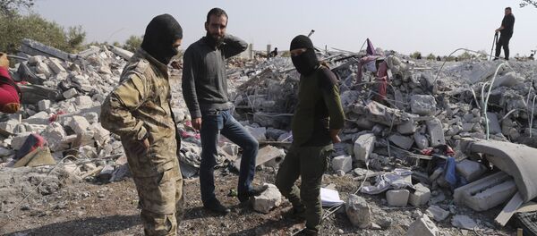أشخاص ينظرون إلى المنازل المدمرة بالقرب من قرية باريشا في محافظة إدلب السورية بعد عملية قام بها الجيش الأمريكي وقال إنها استهدفت أبو بكر البغدادي - سبوتنيك عربي