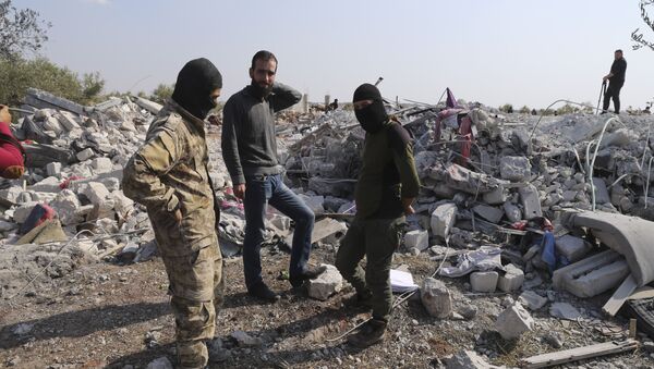 أشخاص ينظرون إلى المنازل المدمرة بالقرب من قرية باريشا في محافظة إدلب السورية بعد عملية قام بها الجيش الأمريكي وقال إنها استهدفت أبو بكر البغدادي - سبوتنيك عربي