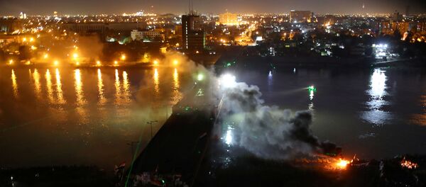 الدخان يتصاعد مع متظاهرين عراقيين يتشاجرون مع شرطة مكافحة الشغب خلال الاحتجاجات المناهضة للحكومة الجارية على جسر الجمهورية في بغداد - سبوتنيك عربي