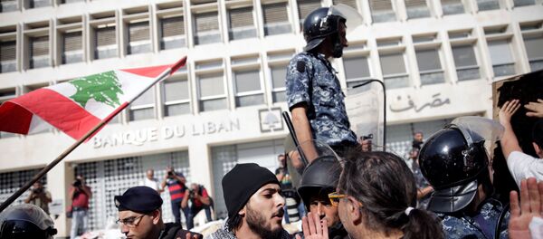 ضباط الشرطة يقفون حذرًا بعد أن قام المتظاهرون بهدم السياج أثناء تظاهرهم خارج البنك المركزي اللبناني خلال الاحتجاجات المستمرة المناهضة للحكومة في بيروت - سبوتنيك عربي