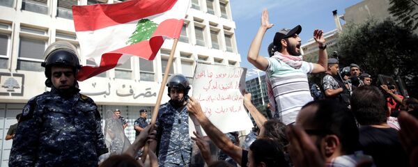 ضباط الشرطة يقفون حذرًا بعد أن قام المتظاهرون بهدم السياج أثناء تظاهرهم خارج البنك المركزي اللبناني خلال الاحتجاجات المستمرة المناهضة للحكومة في بيروت - سبوتنيك عربي