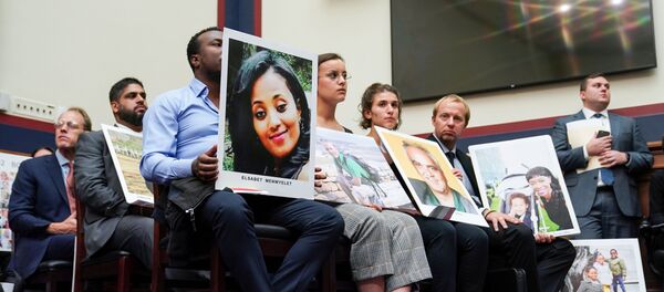 عائلات الضحايا يحملون صوراً لضحايا تحطم طائرة بوينغ 737 ماكس 8 بينما يشهد الرئيس التنفيذي لشركة بوينغ دينيس مويلنبورغ أمام لجنة النقل والبنية التحتية في مبنى الكابيتول هيل في واشنطن - سبوتنيك عربي