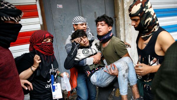 متظاهرون عراقيون يحملون رجلاً متأثراً بالغاز المسيل للدموع أثناء الاحتجاجات المستمرة المناهضة للحكومة في بغداد - سبوتنيك عربي